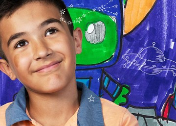 boy with children's drawing of an alien in the background