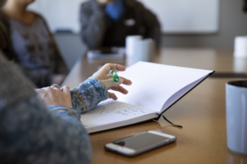 A hand gesturing while taking notes during a meeting.