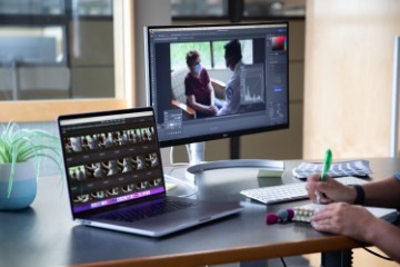 Two people reviewing thumbnails from an editing program.